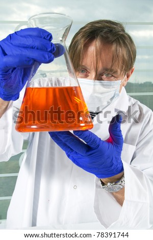 Chemistry scientist looking his red mix with blue latex gloves