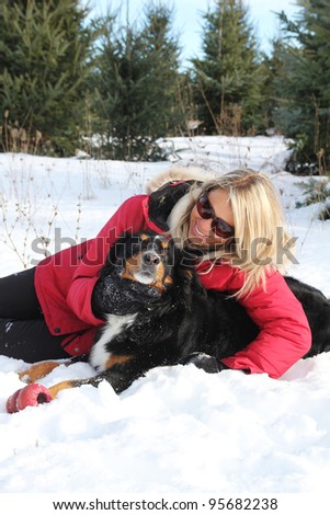 Woman with red jacket taking care of her dog in snow