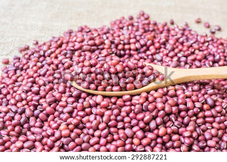 red beans in spoon and pile of red beans on sack cloth