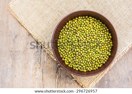 green beans in dish with sackcloth on old wooden background