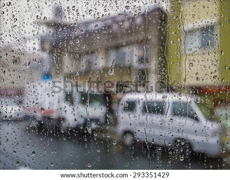 blurred image of traffic view through a car window covered in rain