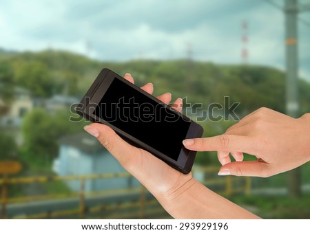 Woman hand holding smart phone against on nature background