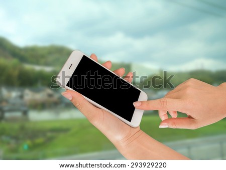 Woman hand holding smart phone against on nature background