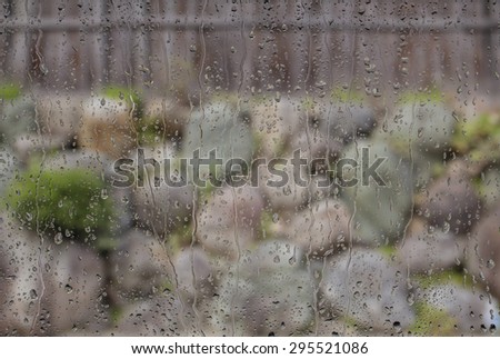 Water drops on a window glass after the rain. The stone walls on background.