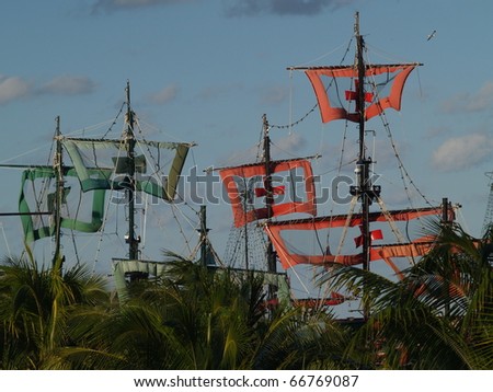 Masts and sails of mock pirate ships rise above palm trees near Cancun Mexico\'s Hotel Strip