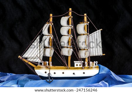 Model white sailboat with three masts on a black