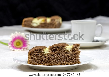 Homemade cocoa cake with cream cheese cup of coffee and flowers