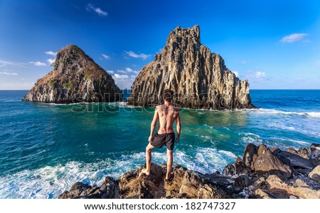 Man standing in the middle of twin brothers rocks, Fernando de Noronha ,Brazil