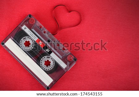 Valentines day card. Vintage audio cassette with loose tape shaping a heart on red background