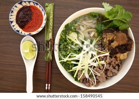 Vietnamese rice noodles are served with beef, lime, bean sauce and chili sauce and ready to eat.