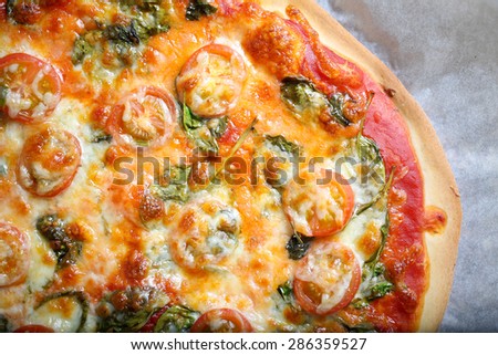 Traditional home made thin crust pizza with spinach, tomato, and mozzarella