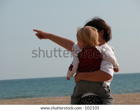 Mother pointing out something to her child on the beach