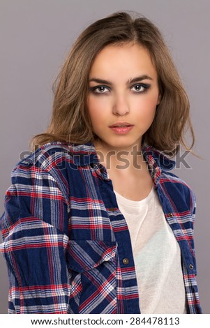 grunge portrait. young beautiful girl in an independent shirt and jeans posing on gray background