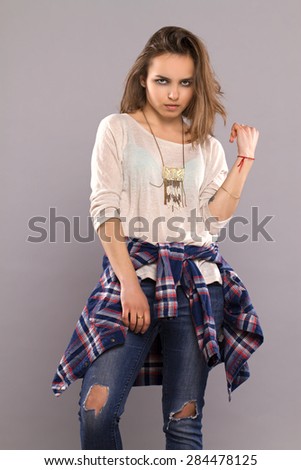 grunge portrait. young beautiful girl in an independent shirt and jeans posing on gray background