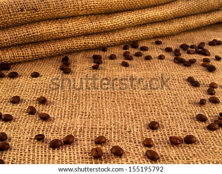Coffee beans on burlap sack background. Natural canvas texture. Empty backdrop for design.