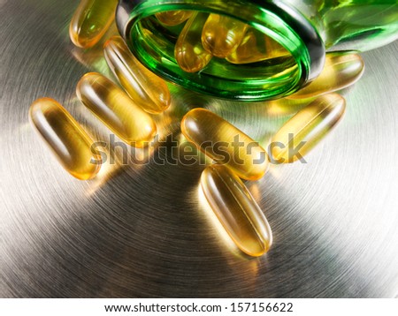 Fish oil capsules and container on metallic background. Medicine background with pills. For immunity.