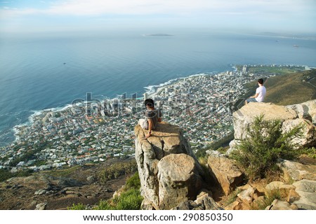 CAPE TOWN, SOUTH AFRICA - DECEMBER 7: Young men looking at view of the cityspace and coast from the edge of Lions Head peak on December 7, 2014 in Cape Town, south Africa.