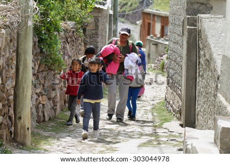 SAN ISIDRO, ARGENTINA - APRIL 7: Indigenous woman and kids in the narrow streets of the remote village of San Isidro on April 7, 2015 in San Isidro, Argentina. No roads arrive to this remote village.