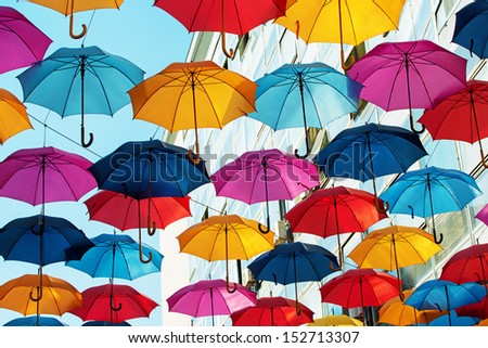 Many colorful umbrellas strung across the street.