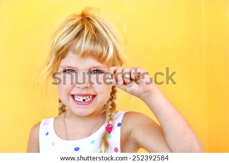 Smiling girl holding missing tooth
