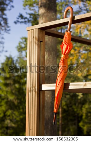 Orange umbrella hanging on wooden terrace