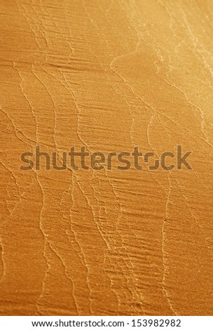 Wavy patterns of wet river sand on the beach. Gradient of sandy brown color.