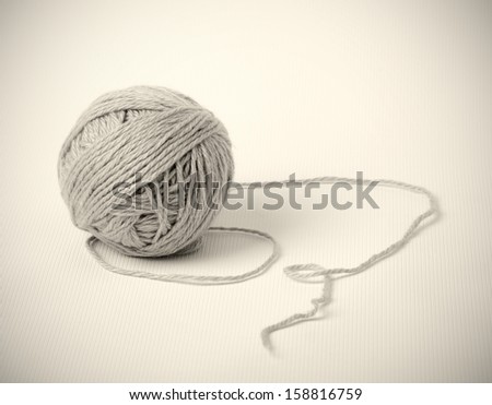Single grey skein lies on white textile. End of thread is located around clew. The photo is vignetted.