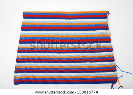 Rectangular bit of knitted cloth is isolated on white. Multicolored fabric is knitted by hand. It has horizontal pattern composed of red, white, blue, orange stripes.