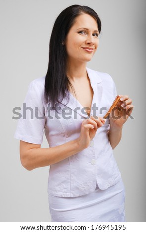 A pretty businesswoman is standing and holding a pen. The friendly woman is looking at the camera and smiling.