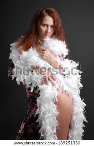 Young woman wraps herself in a dressing-gown, her hip and hands peep out feathers.