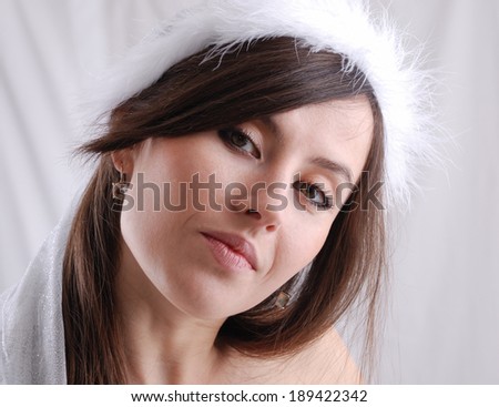 Portrait of the dark-haired girl in the cap trimmed with down, suspicious look, head tilted sideways