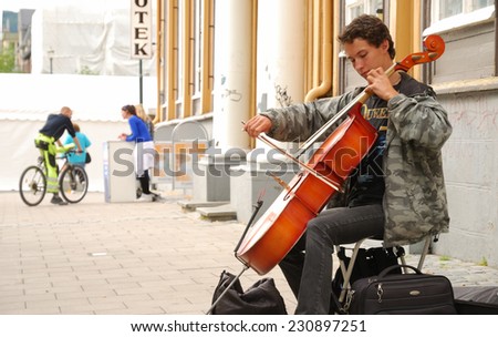 TRONDHEIM, NORWAY - JULY 26 2010: A street musician plays his violoncello in the summer street in TRONDHEIM, NORWAY - JULY 26 2010.