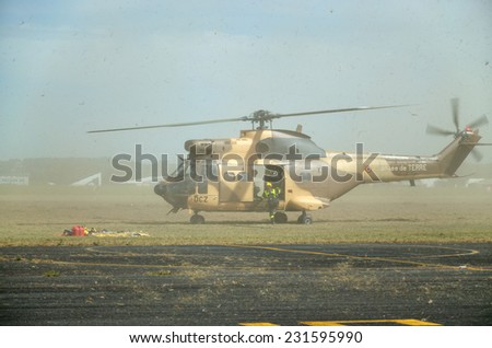 A modern military gunship is landing on the green field for evacuation.