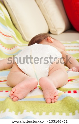 Feet of newborn baby boy seven weeks age sleeping on couch