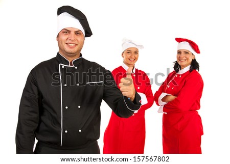 Successful team of three chefs with teacher chef in front of image giving thumbs