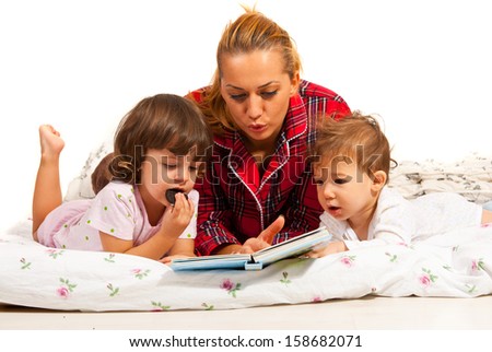Mother reading bedtime story to her  children  in bed