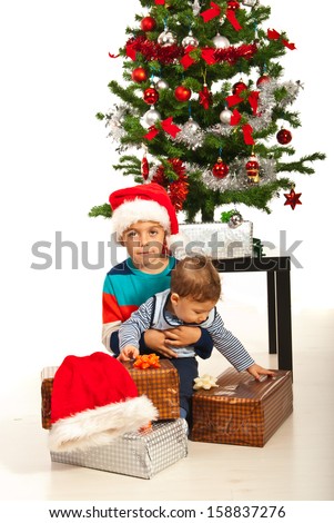 Big brother holding his baby brother in front of Christmas tree