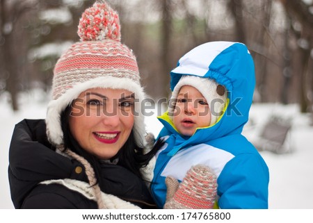 Happy mother holding baby in winter park