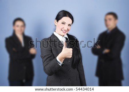 Business woman leader giving thumbs up in the middle of her colleagues and smiling,concept of successful teamwork