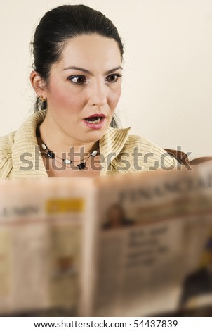 Shocked woman reading bad news in newspaper