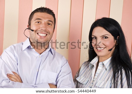 Happy smiling support operator team ,man and woman with headphones in front of vertical blinds