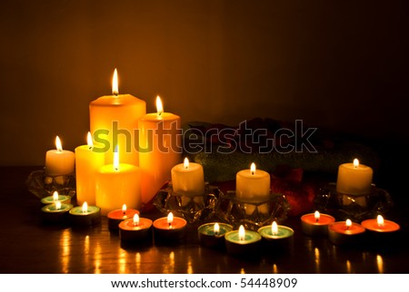 Arrangement for spa with candle lights,towels and petals in darkness on wood table