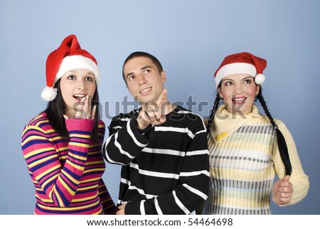 Wow!Look their!The young man pointing somehwere and the girls with Santa hats showing a surprised face and looking up