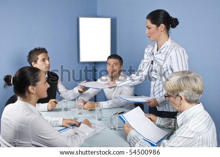 Group of  business people at meeting table sitting on chair while a business young woman giving all folders with papers