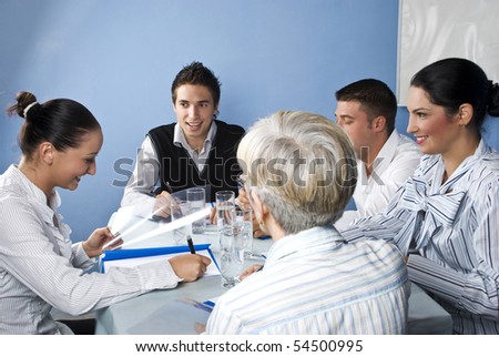 Group of five people having fun and laughing at business meeting on blue background