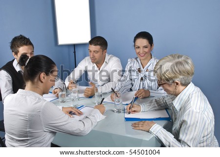 Five business people at meeting have a discussion and they are cheerful and laughing together