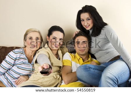 Happy group of friends or family watching tv and smiling