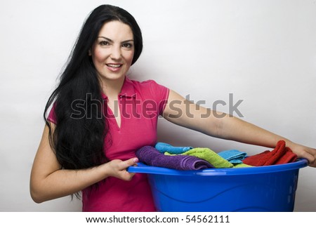 Smiling beauty housewife holding a blue basket with clean laundry