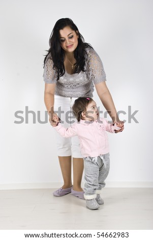 Young mother helping her baby girl to make first steps