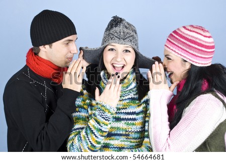Three friends having fun,two of them trying to tell a secret to girl in middle at her cap ears and all laughing together